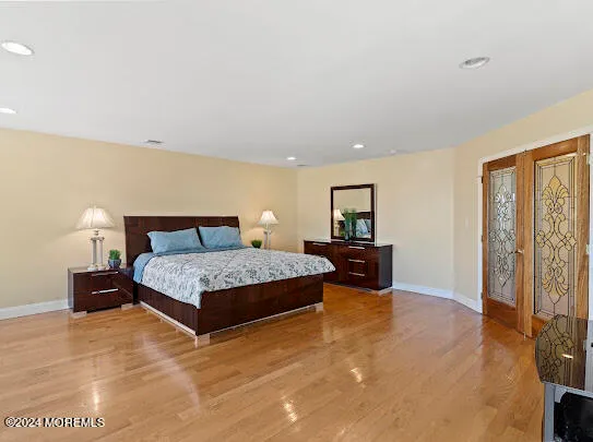 a spacious bedroom with a bed and wooden floor