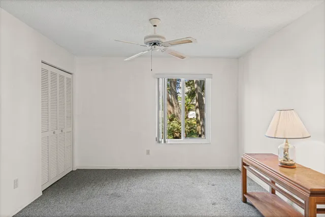 an empty room with windows and fan