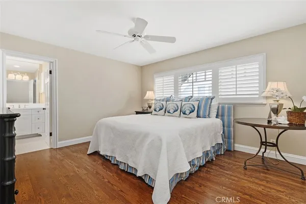 a bedroom with a bed a table and chair with wooden floor