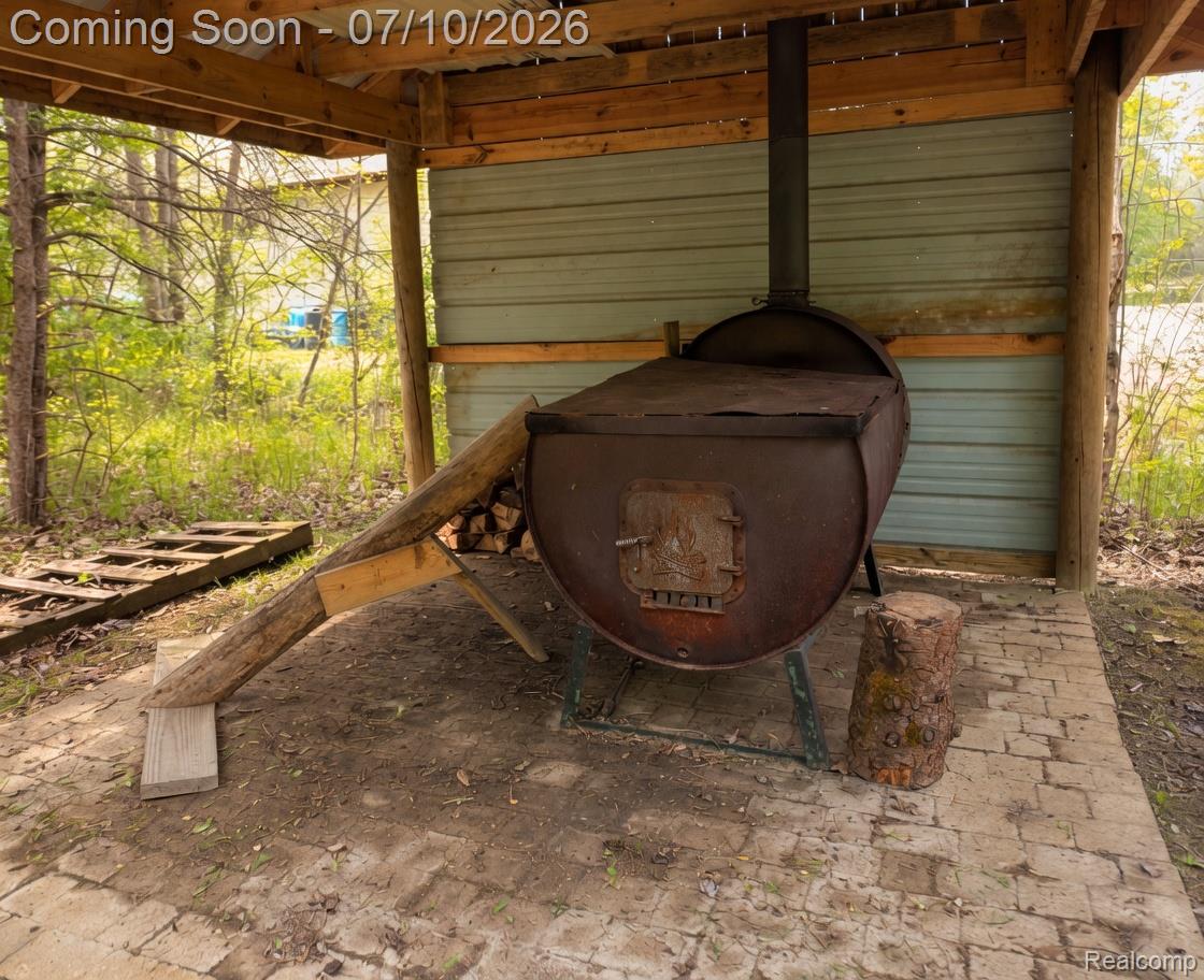 5278 Skelton Road Columbiaville, MI 48421 - Photo 18 of 64 Covered outdoor cooking area featuring a large, rustic metal smoker with a chimney, set on a brick paver base