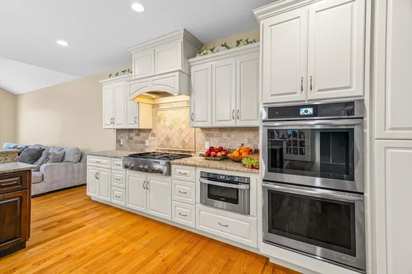 a kitchen with stainless steel appliances granite countertop a stove and white cabinets