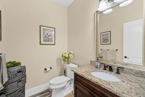 a bathroom with a granite countertop toilet a sink and a mirror
