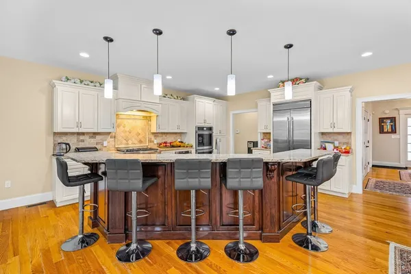 a kitchen with stainless steel appliances granite countertop a stove a refrigerator a oven a sink with a dining table and chairs