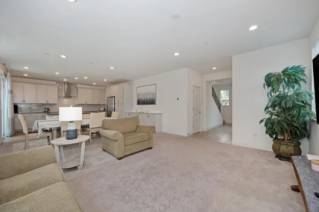 a living room with furniture a potted plant and kitchen view