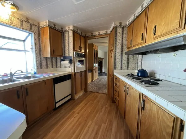 a kitchen with stainless steel appliances granite countertop a sink cabinets and wooden floor