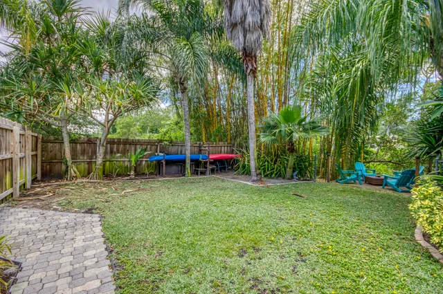 a view of a yard with a table and chairs a barbeque and a large trees