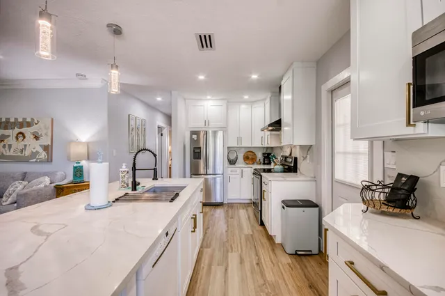 a view of a kitchen with kitchen island a sink stainless steel appliances and cabinets