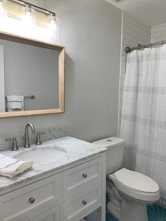 a bathroom with a granite countertop toilet sink and mirror