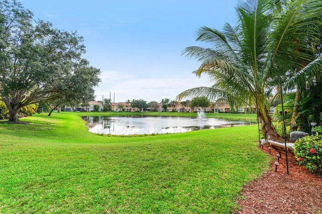 a view of a house with a big yard and palm trees