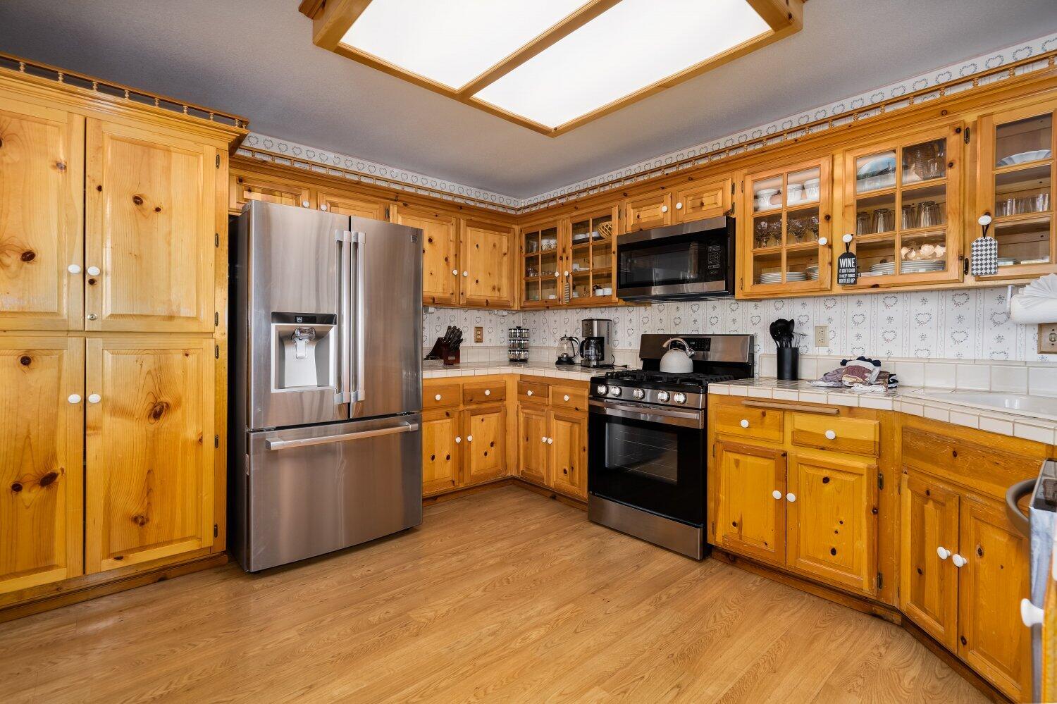 42363 Paramount Road Big Bear Lake, CA 92315 - Photo 13 of 38 a kitchen with stainless steel appliances granite countertop a refrigerator oven a sink dishwasher and white cabinets with wooden floor