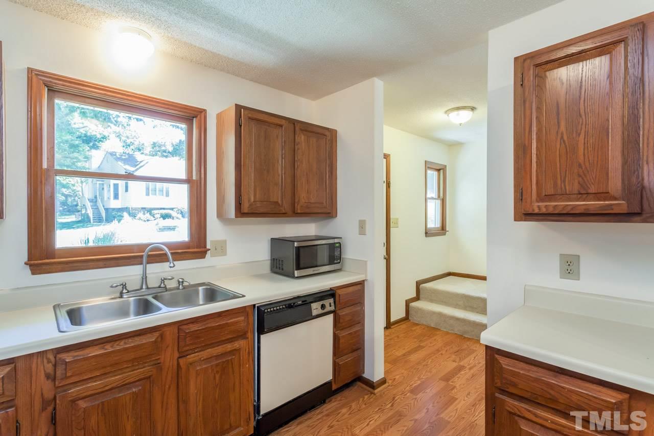 6679 English Ivy Lane Raleigh, NC 27615 - Photo 3 of 24 a kitchen with stainless steel appliances granite countertop wooden cabinets a sink and a window
