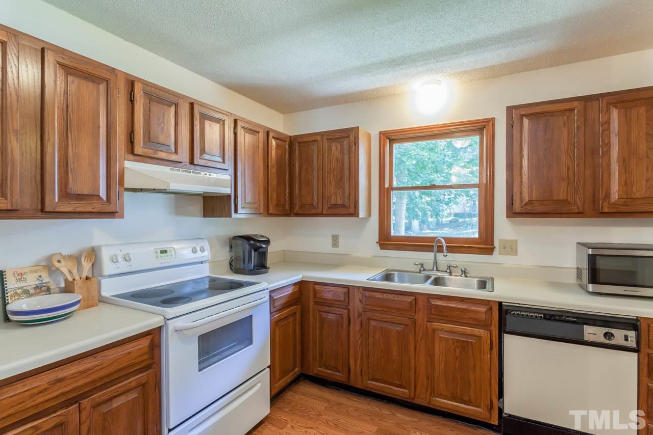 6679 English Ivy Lane Raleigh, NC 27615 - Photo 4 of 24 a kitchen with stainless steel appliances granite countertop a sink stove cabinets and window