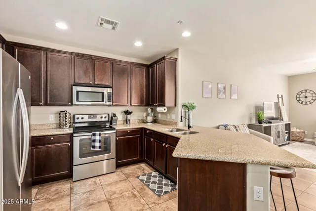 a kitchen with stainless steel appliances granite countertop a sink stove refrigerator and cabinets