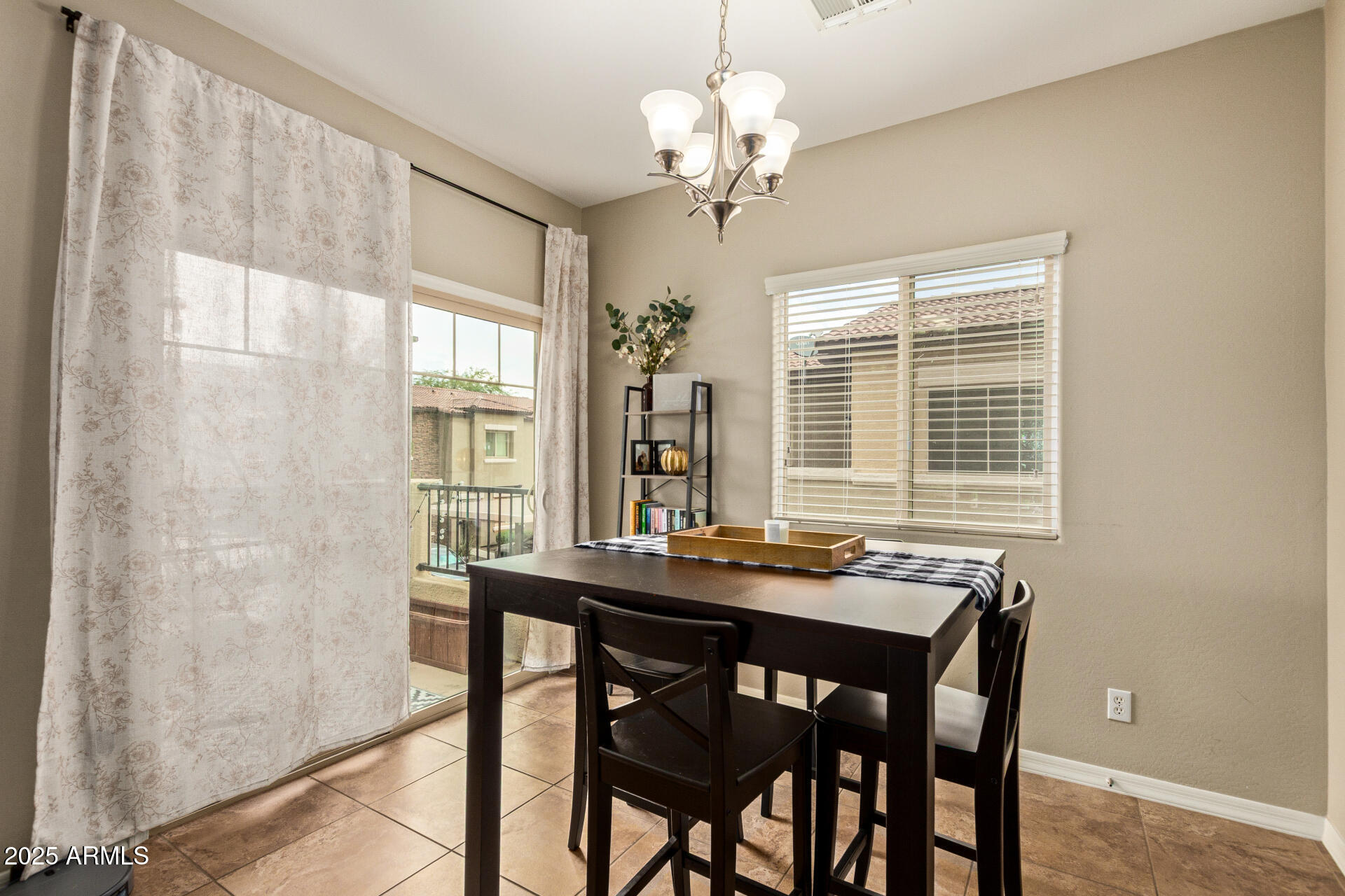 7726 East Baseline Road, Unit 234 Mesa, AZ 85209 - Photo 9 of 31 a dining room with wooden floor a chandelier a wooden table and chairs