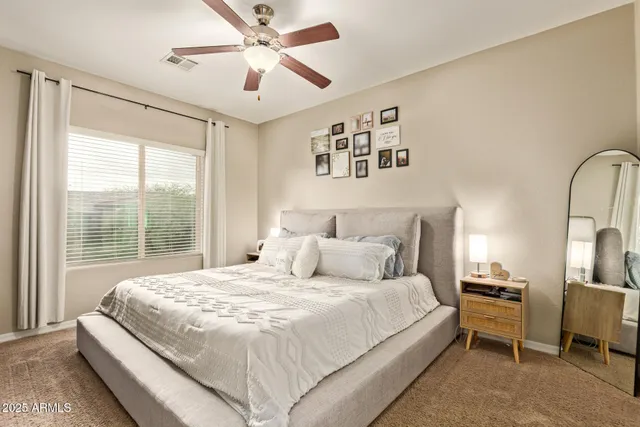 a large bedroom with a large bed and a chandelier fan
