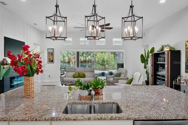 a kitchen with stainless steel appliances kitchen island granite countertop a dining table chairs and white cabinets