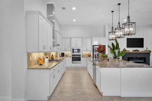 a large kitchen with stainless steel appliances kitchen island granite countertop a sink and white cabinets