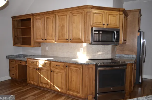 a kitchen with granite countertop a stove and a microwave