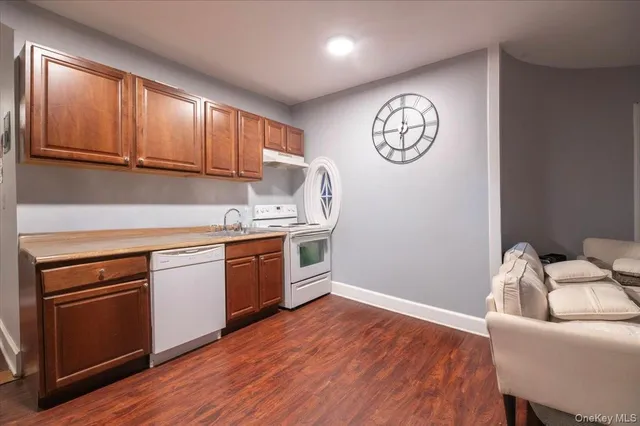 a kitchen with granite countertop a refrigerator a stove a sink and dishwasher with wooden floor