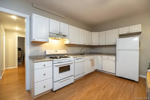 a kitchen with granite countertop white cabinets and white appliances