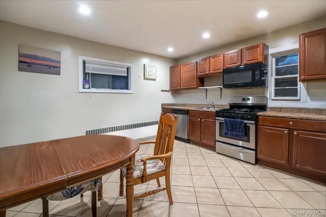 a kitchen with stainless steel appliances granite countertop a stove top oven a sink a dining table and chairs