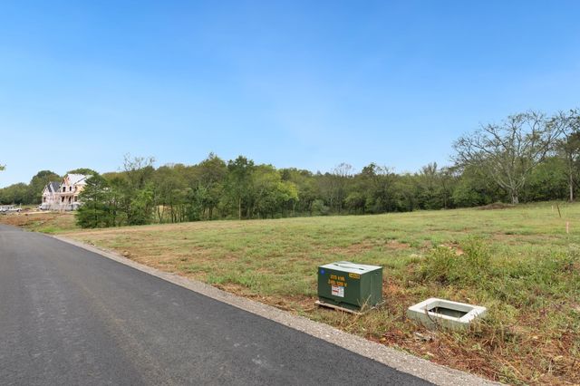 an aerial view of a residential houses with outdoor space and trees all around