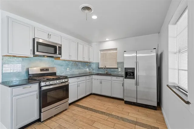 a kitchen with white cabinets stainless steel appliances and a window
