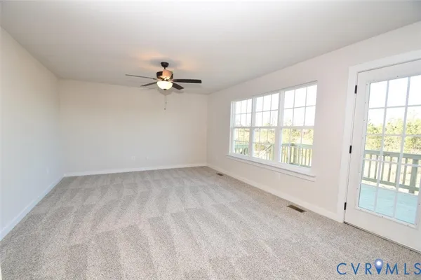 an empty room with chandelier fan and windows