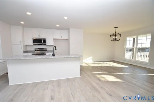 a kitchen with stainless steel appliances granite countertop a stove a sink and a microwave