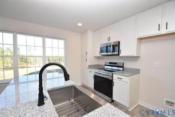 a kitchen with stainless steel appliances granite countertop a stove a sink and a microwave