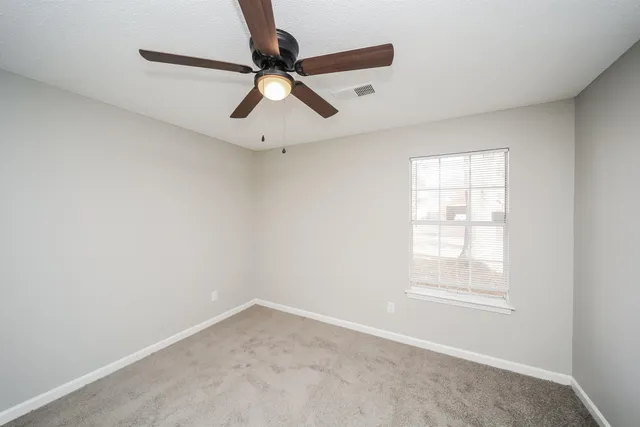 an empty room with windows and fan