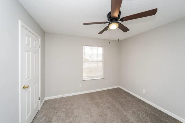 an empty room with a window and a fan