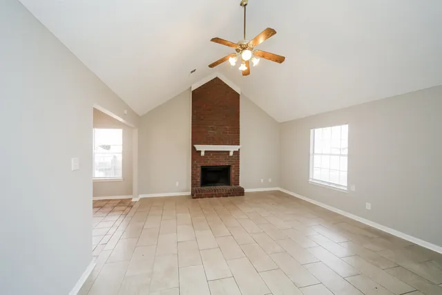 an empty room with chandelier fan and windows