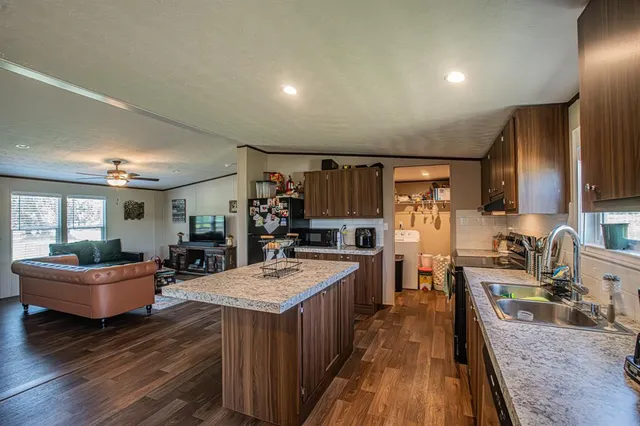 a large kitchen with sink a refrigerator a stove and a dining table with wooden floor