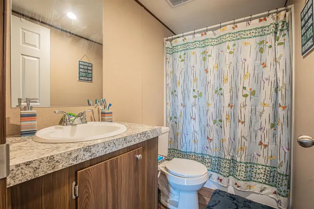 a bathroom with a granite countertop sink toilet and a mirror