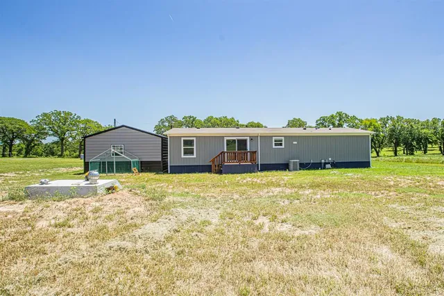 a front view of house with yard and trees in the background