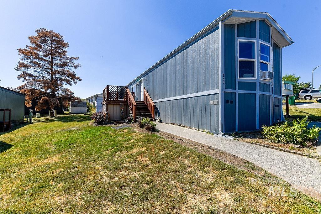 View of property exterior with a yard and stairs