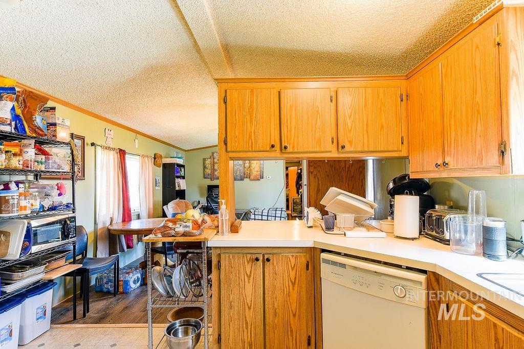 609 North Almon Street, Unit 3022 Moscow, ID 83843 - Photo 11 of 26 Kitchen with dishwasher, light countertops, crown molding, wood finish cabinetry, and dark wood-style floors