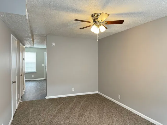 an empty room with closet and a chandelier fan