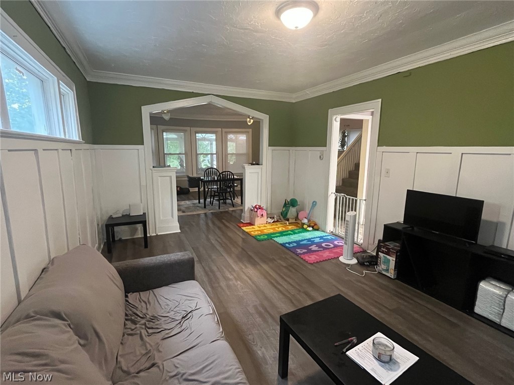 1101 Carlyon Road East Cleveland, OH 44112 - Photo 7 of 23 Living space featuring new flooring, wainscoting, crown molding, and an arched entryway