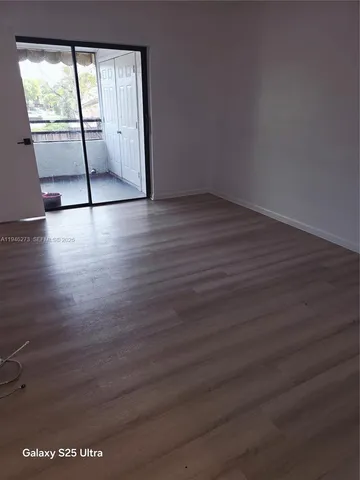 a view of an empty room with wooden floor and glass door
