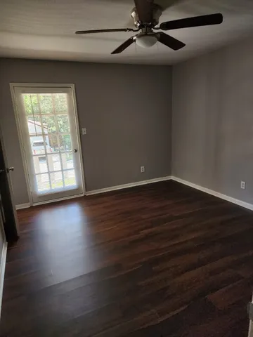 an empty room with wooden floor fan and windows