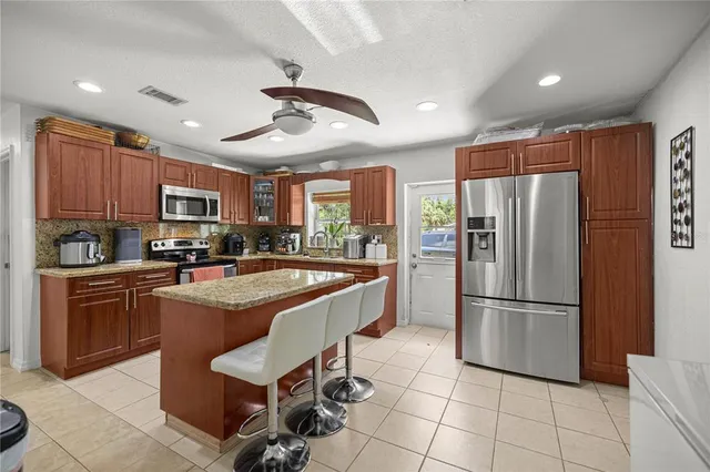 a kitchen with stainless steel appliances granite countertop a refrigerator a stove top oven a sink dishwasher and a refrigerator