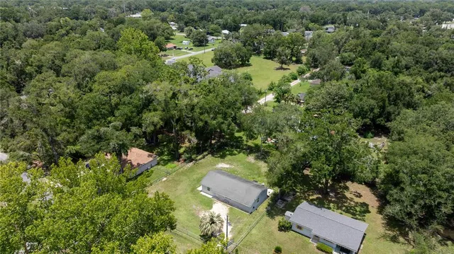 an aerial view of residential house with outdoor space and trees all around