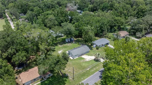 an aerial view of residential house with outdoor space and trees all around