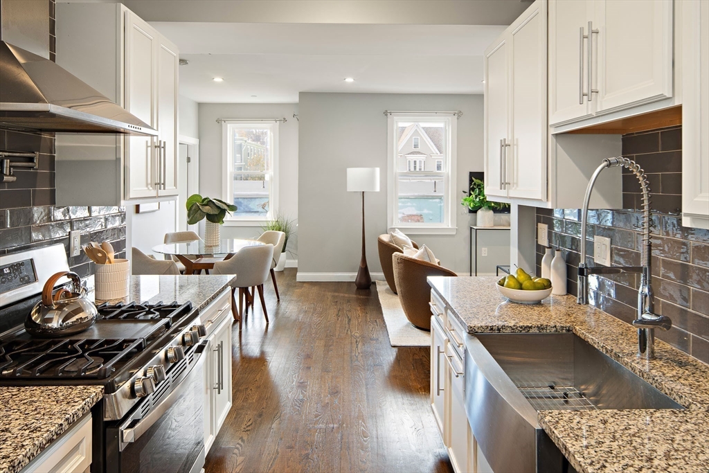 9-11 Boynton Street, Unit 2 Boston, MA 02130 - Photo 7 of 30 a kitchen with stainless steel appliances granite countertop a stove top oven a dining table and chairs with wooden floor