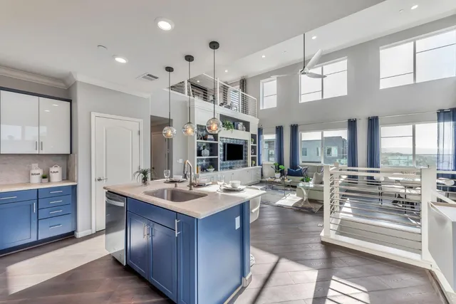 a living room with stainless steel appliances granite countertop a sink dishwasher a stove and a dining table with wooden floor