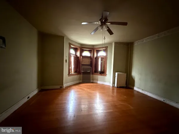 a view of an empty room with window and wooden floor