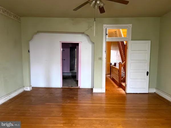 a view of a hallway with wooden floor and a room