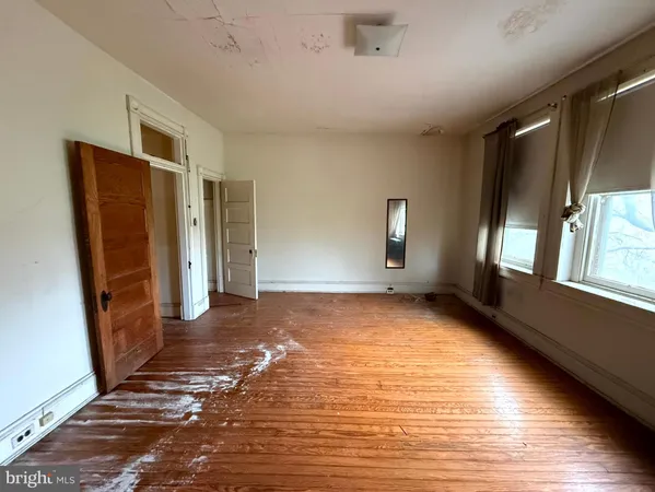 a view of an empty room with window and wooden floor